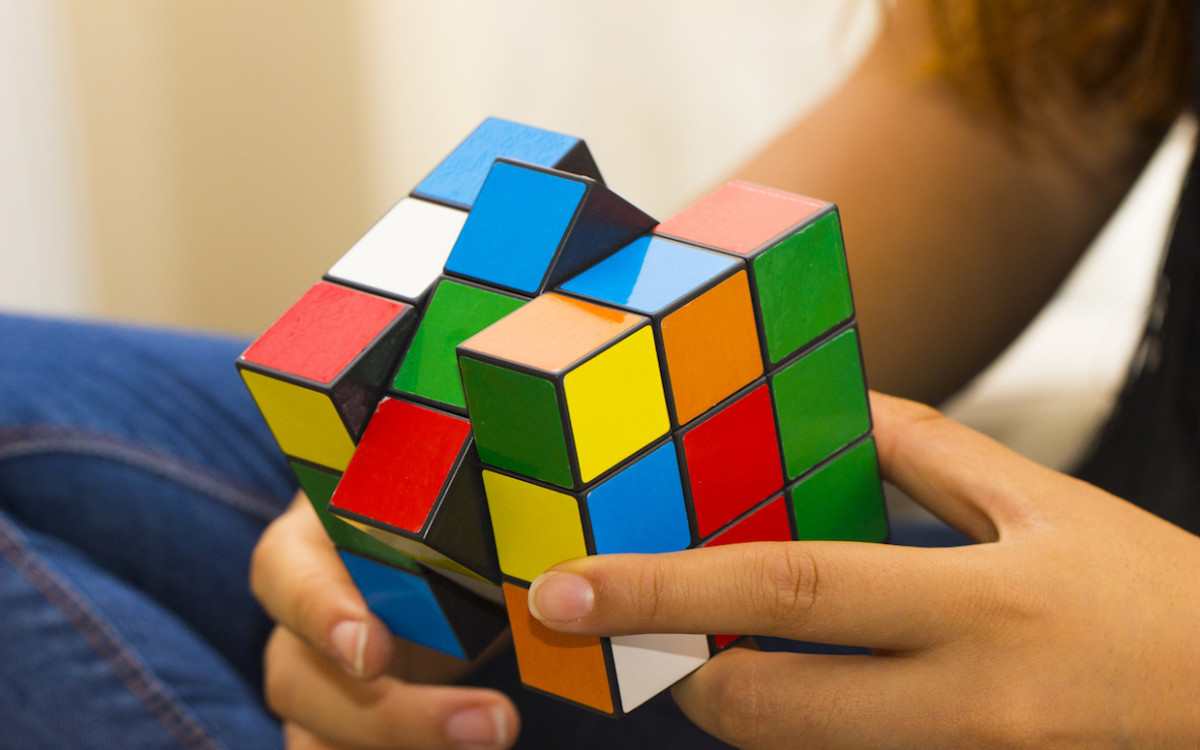 A person sitting down solving a rubix cube