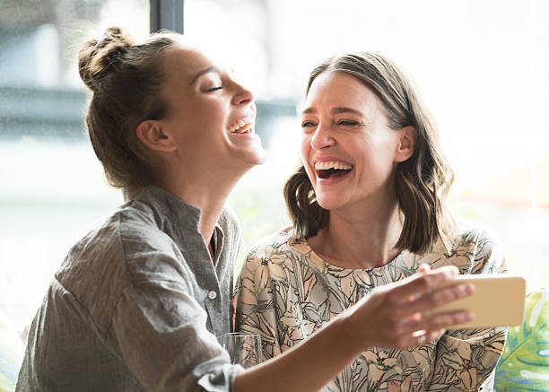 Two girls laughing together looking at a phone