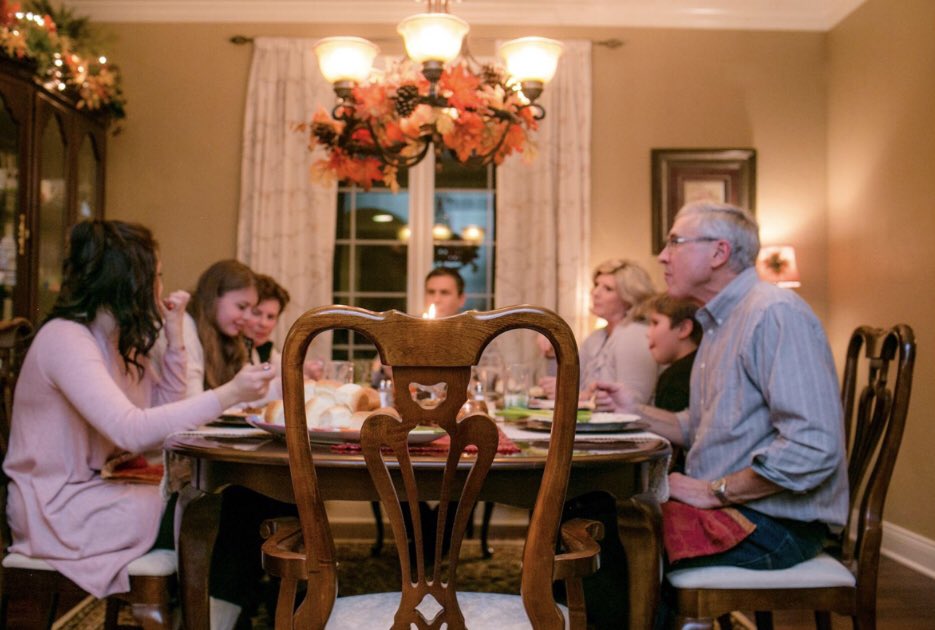 A family having dinner around a table with one open seat at the end in focus