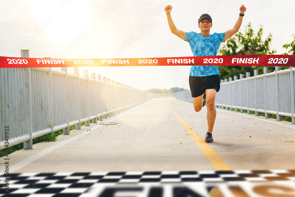 A woman with her arms up crossing the finish line of a marathon