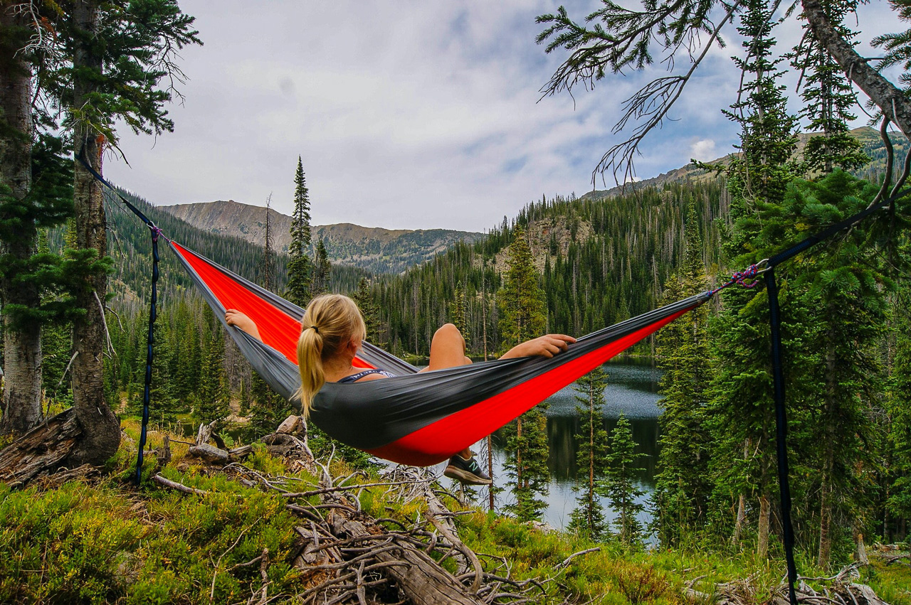 A girl in a hamock surrounded by trees and grass