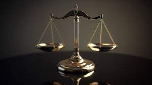 A gold scale of justice sitting on a table with a dark background