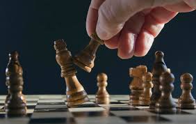 A hand moving a chess piece to knock down another piece