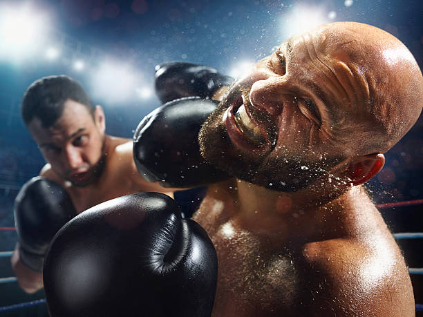 A boxer punching another boxer in the face inside an arena with lights