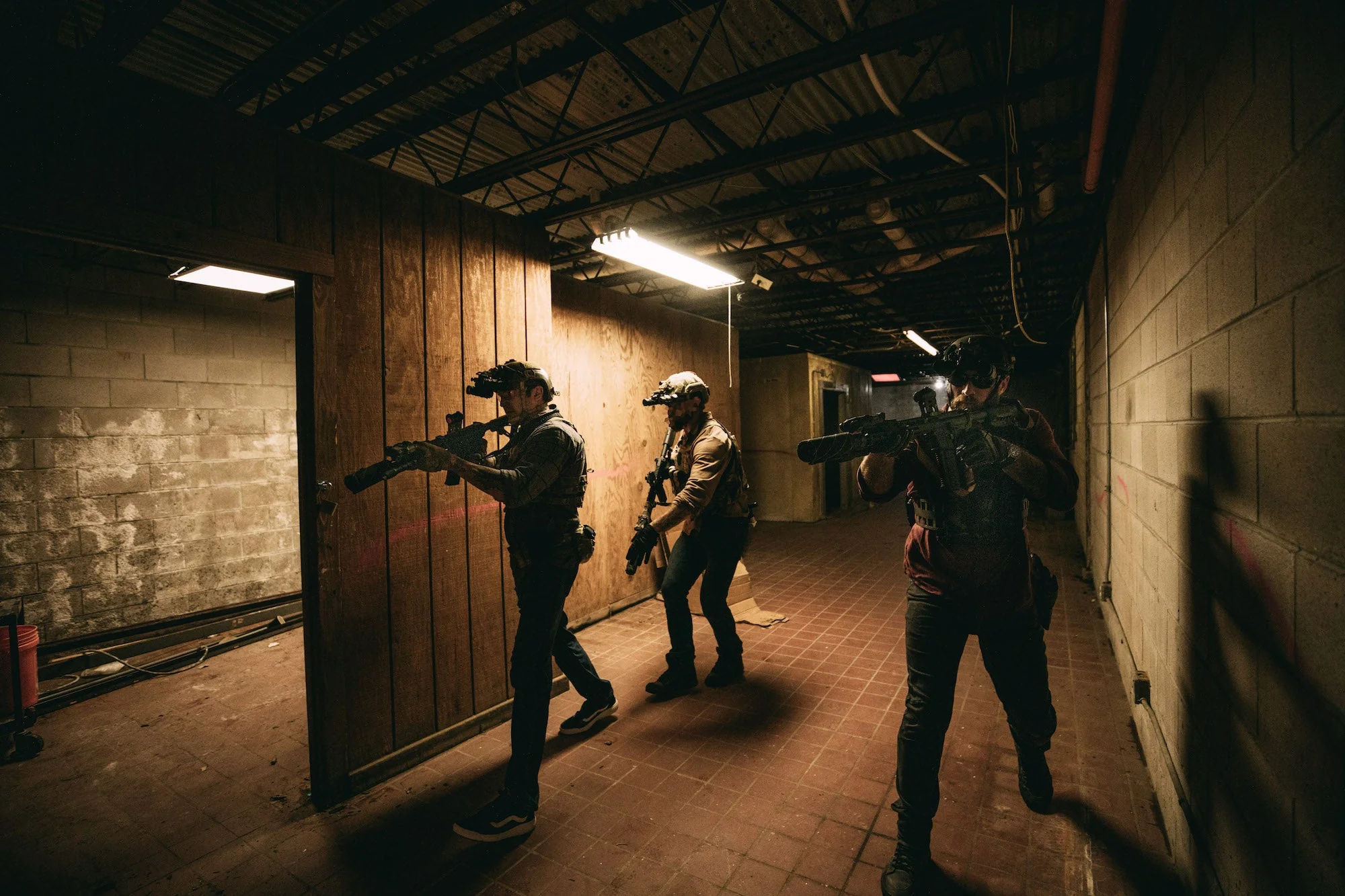 Three people in gear armed navigating a building of stone