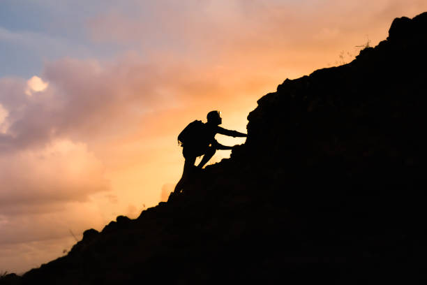 A person climbing a mountain with the sunset in the background